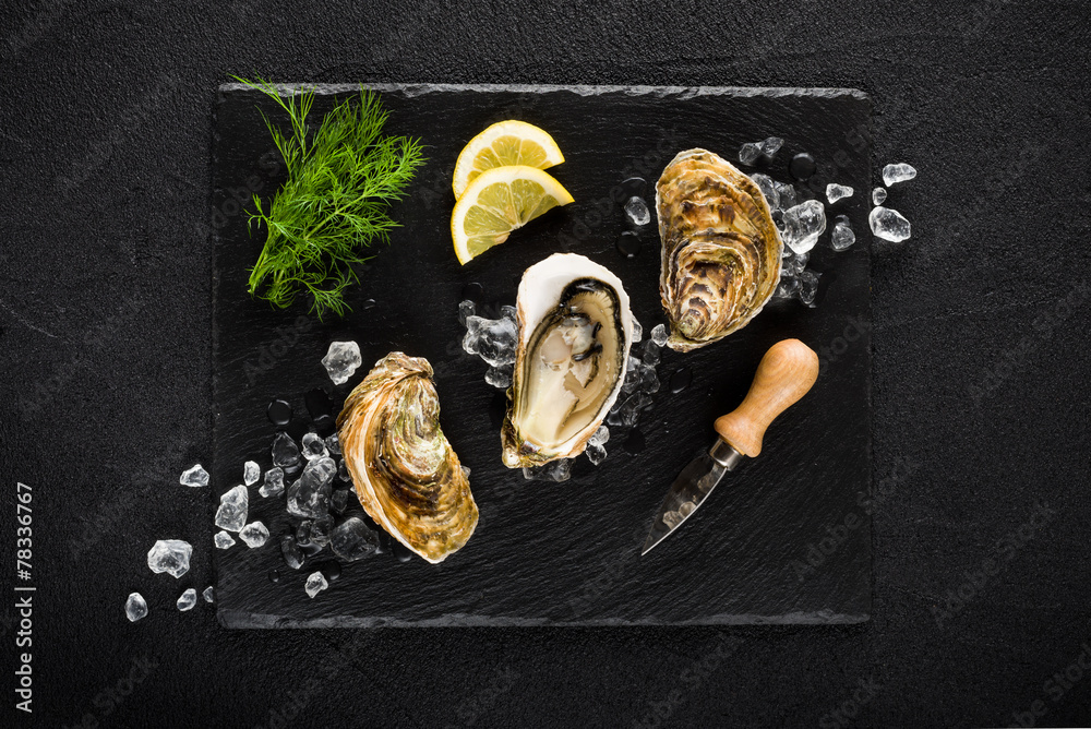 Fresh oysters on a black stone plate top view