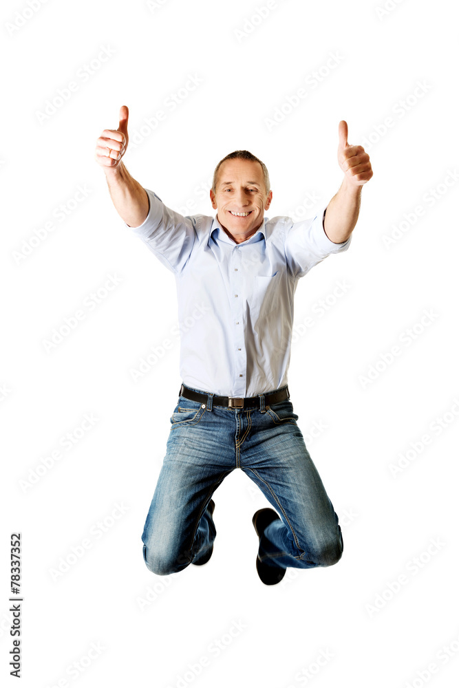 Mature man jumping with thumbs up