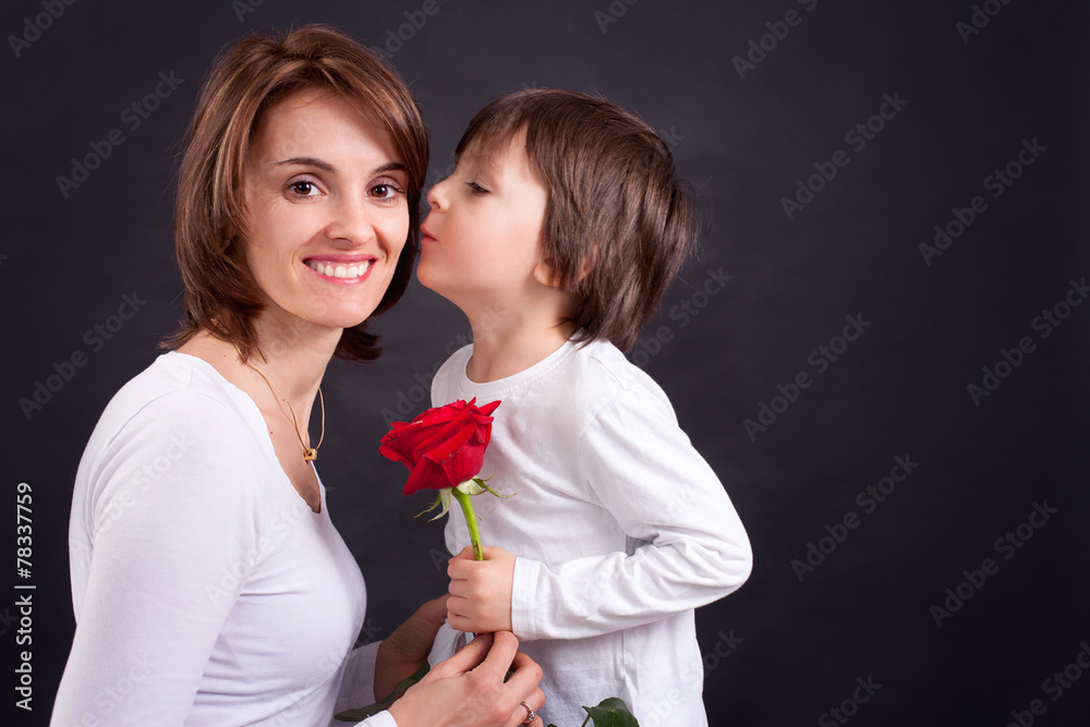 Young kid giving gorgeous red rose to his mom