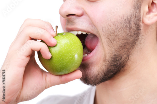 Man biting fresh green apple with healthy teeth isolated