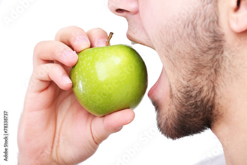 Man biting fresh green apple with healthy teeth isolated