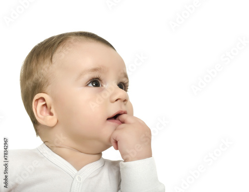 Cute baby boy with hand in the month looking up curiously.