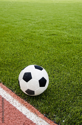 The football is on the artificial grass soccer field in the stadium.