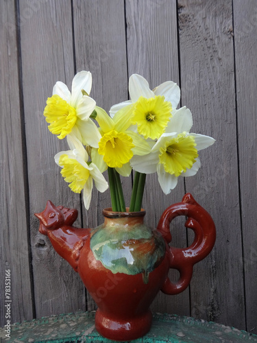 daffodils  in a vase on a wooden background gray boards photo