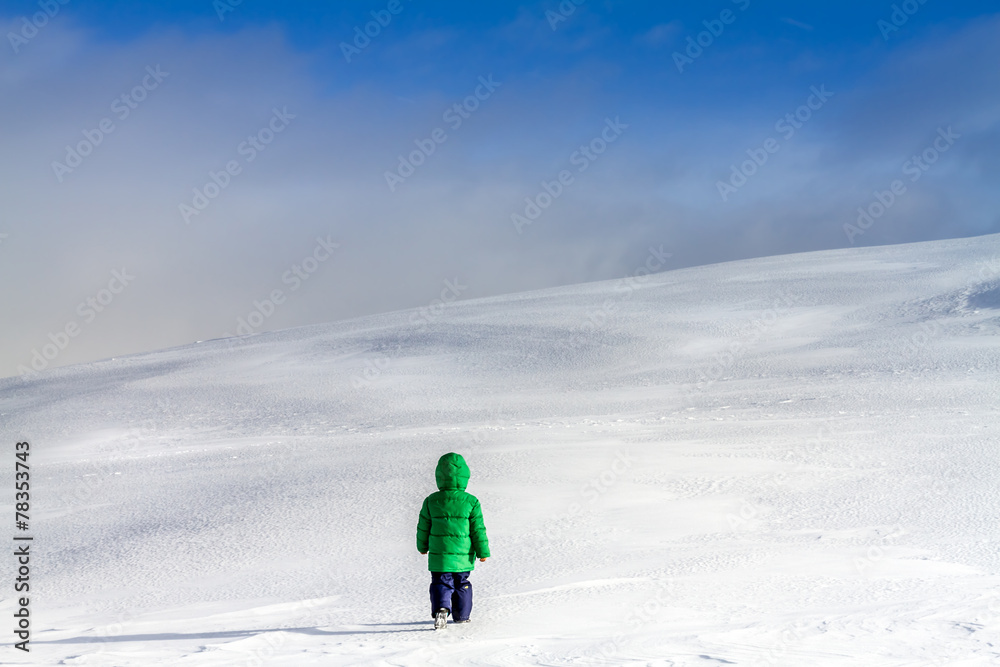 An adventurous little boy walking in the clouds in winter