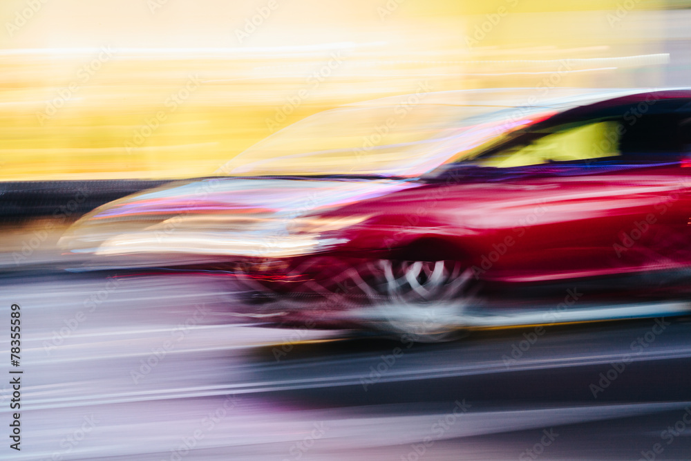 Obraz premium Red Sports Car in a Blurred City Scene