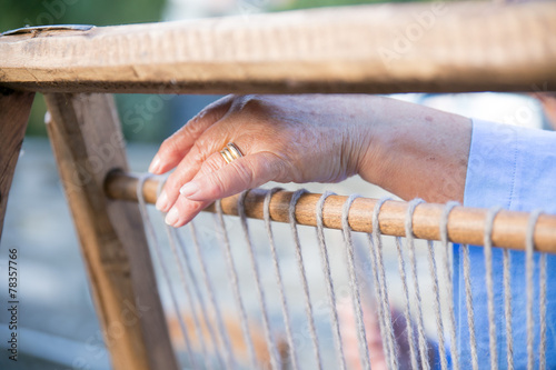 The hand of a weaver using a loom