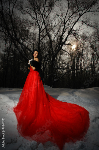Brunette in red dress in the winter forest