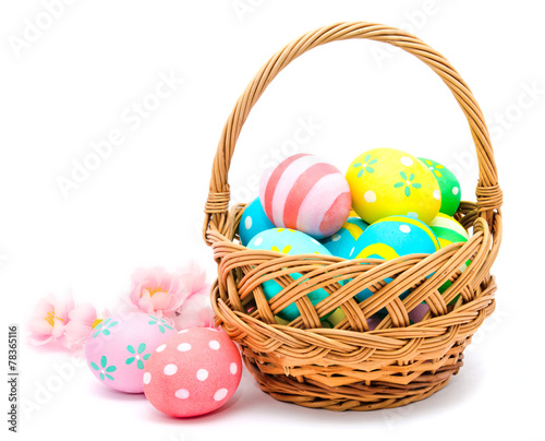 Colorful handmade easter eggs in the basket and flowers isolated