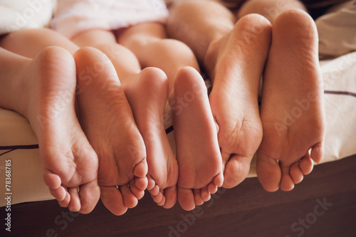 close up of a family showing off their feet under the covers.