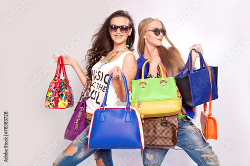 Two fashion girls and many different shopping bags in hands