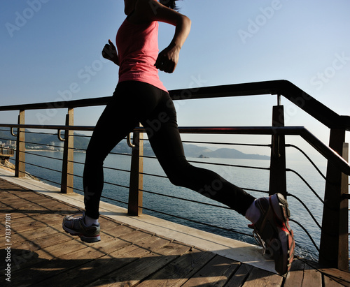 young fitness woman running on sunrise seaside boardwalk