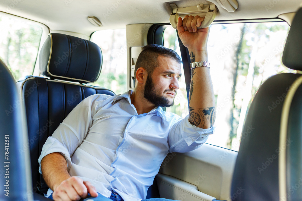 Happy male wit beart and tattoe in a car. Happy male wit beart and tattoe in a car.