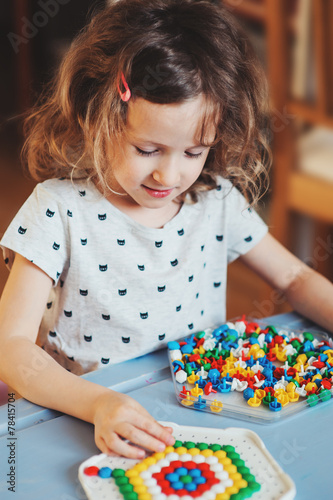 prescholer child girl playing colorful mosaic at home photo