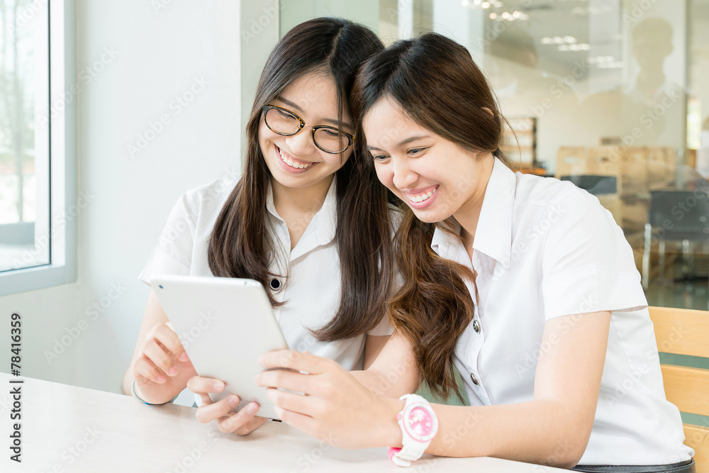 Two student with uniform in classroom with electronic tablet Two student with uniform in classroom with electronic tablet