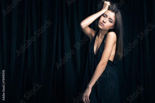 Young girl with black dress against curtains.