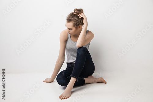 Beautiful melancholic girl sitting on the floor .