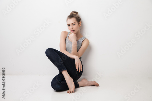 Beautiful melancholic girl sitting on the floor .