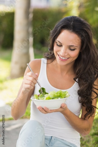 Pretty brunette eating bowl of salad