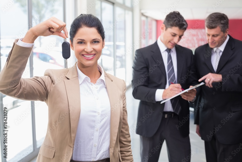 Smiling saleswoman holding a customer car key Smiling saleswoman holding a customer car key