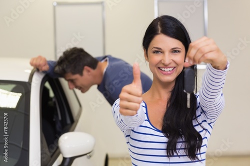 Customer holding her new car key while giving thumbs up