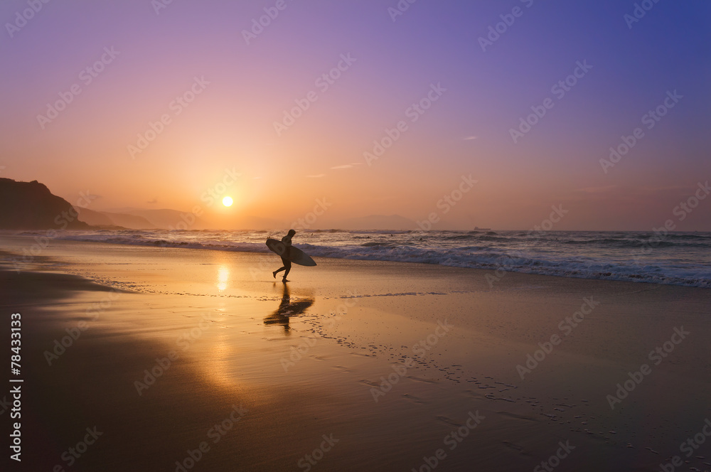 surfer entering water at sunset