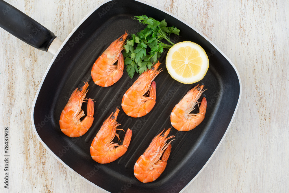 cooked shrimps with lemon and parsley in a pan