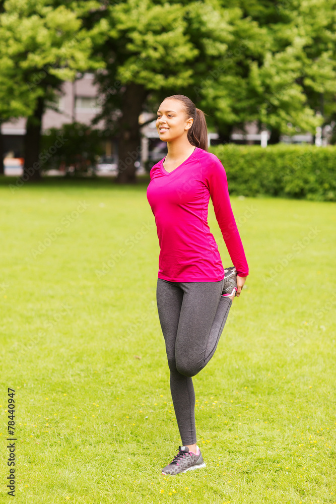 smiling black woman stretching leg outdoors smiling black woman stretching leg outdoors