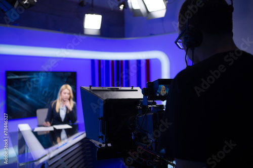 Young beautiful blonde television announcer at studio during live broadcasting.Female TV director at editor in studio.Recording at TV studio with television anchorwoman. TV NEWS studio with camera photo