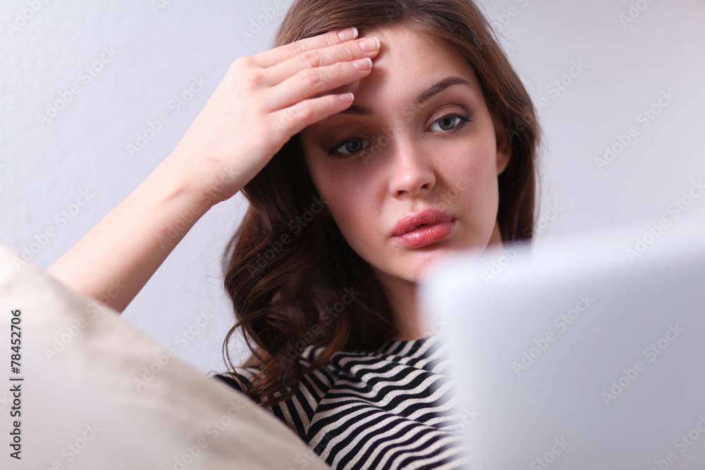 Portrait of a young woman sitting in front her laptop on sofa Portrait of a young woman sitting in front her laptop on sofa
