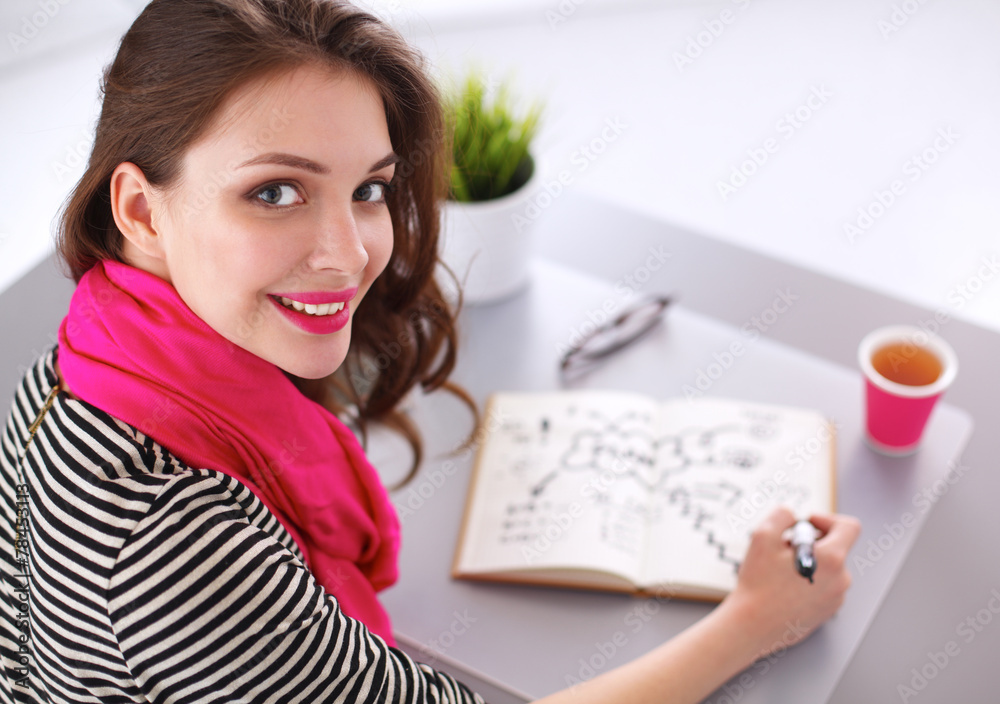 Young woman writes to diary on a white table