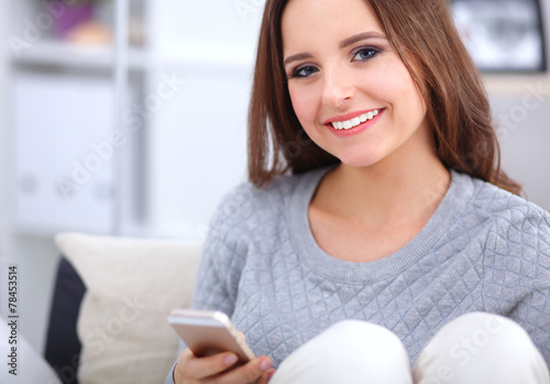 Pretty girl using her smartphone on  couch at home in the living