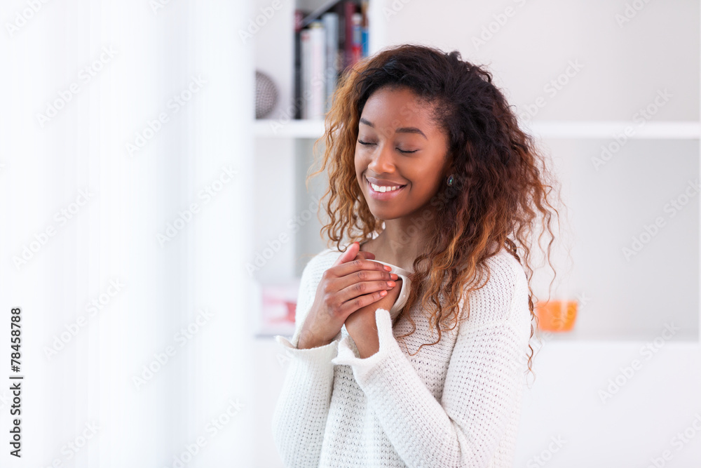 African American woman in her living room drinking holding a cof African American woman in her living room drinking holding a cof