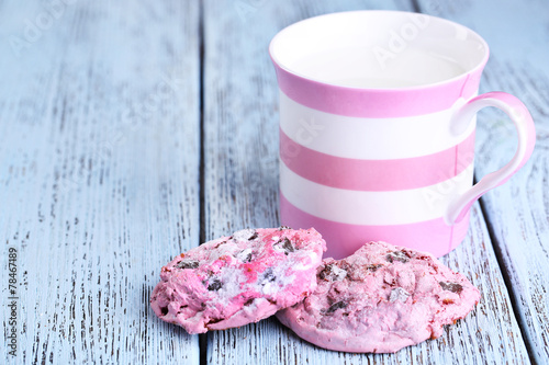 Pink cookies and cup with milk on table close-up