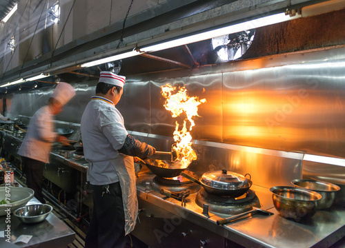 Crowded kitchen, a narrow aisle, working chef.