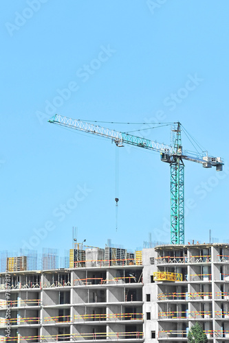 Crane and building construction site against blue sky © Unkas Photo