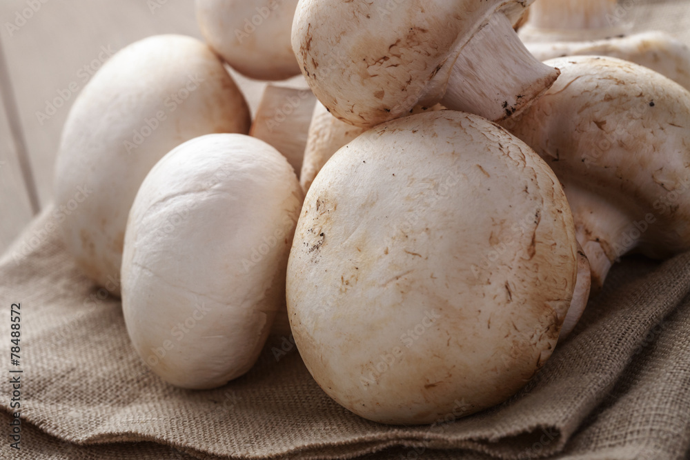 heap of fresh white mushrooms on sack cloth over table heap of fresh white mushrooms on sack cloth over table