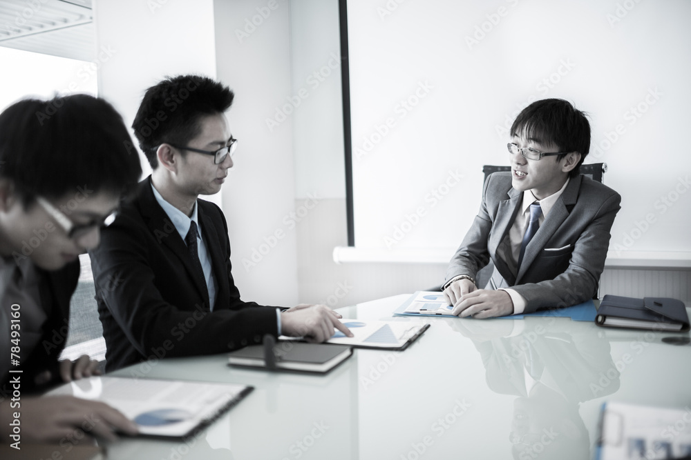 Young business people sitting in board room during meeting and d Young business people sitting in board room during meeting and d