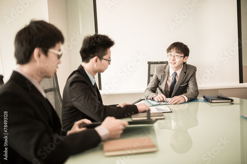 Young business people sitting in board room during meeting and d