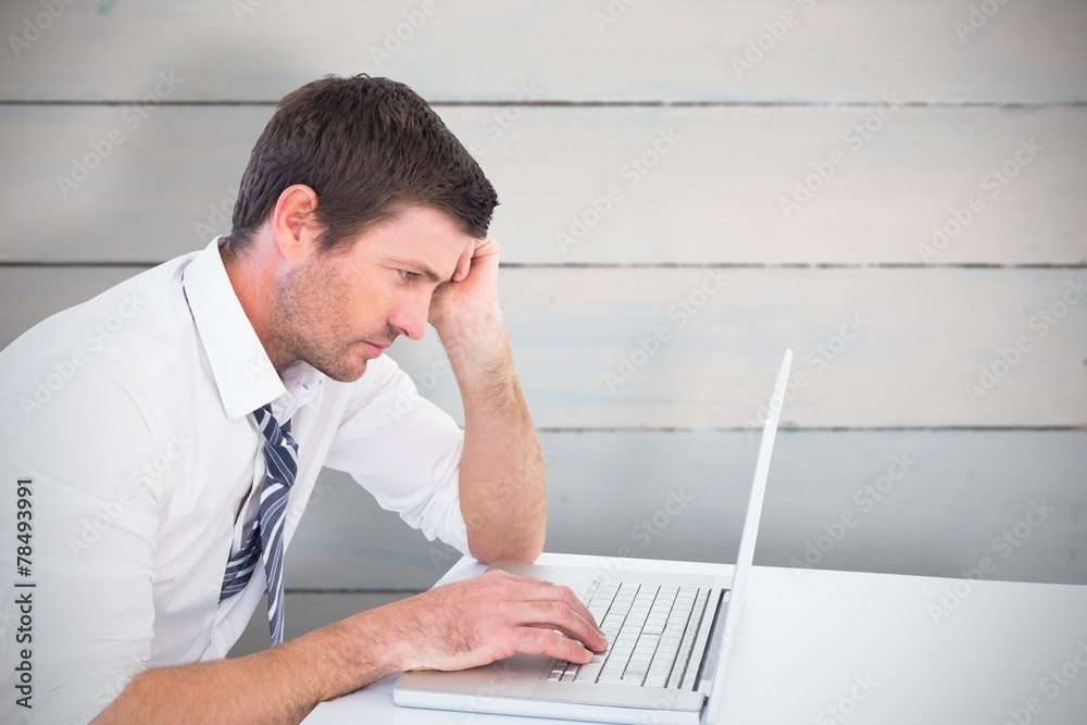 Composite image of focused businessman working on his laptop Composite image of focused businessman working on his laptop