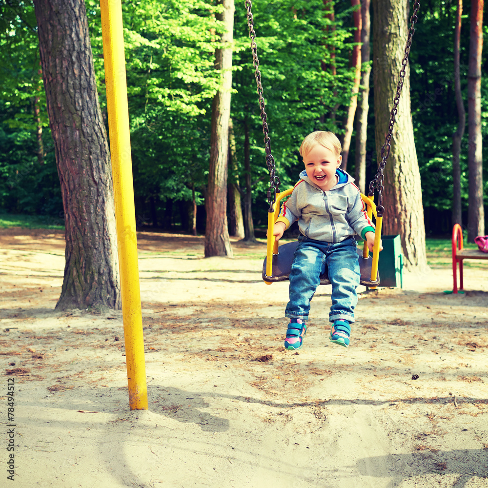 Happy little blond boy having fun on a swing. Happy little blond boy having fun on a swing.