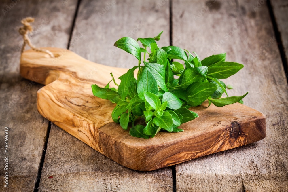 bunch of fresh organic basil in olive cutting board