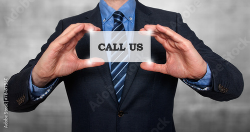 Business man holding Call Us card. Grey background