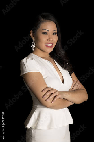 Asian woman in a white dress standing folding her arms smiling