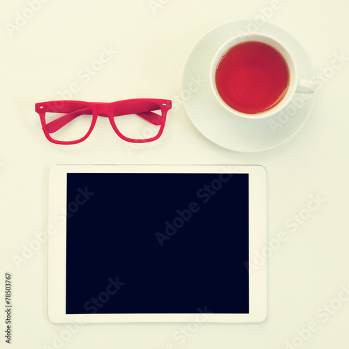 eyeglasses, tablet computer and cup of tea