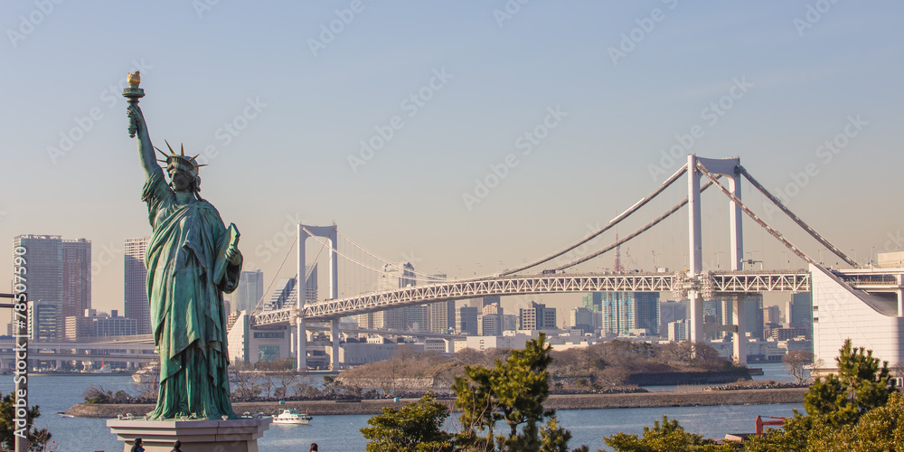 Fototapeta premium Lady liberty juxtaposed against Rainbow Bridge in Tokyo, Japan.