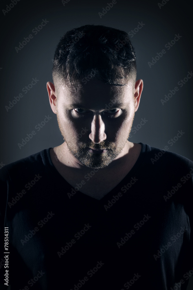 Fototapeta premium Man posing with angry face and dark background with hard lightin