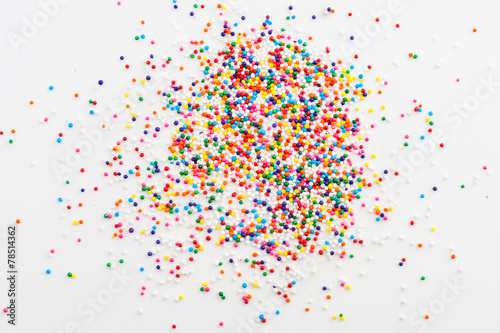 Colorful round sprinkles spilled on white background, isolated photo