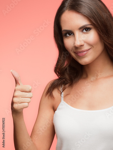 Portrait of happy woman showing thumb up gesture, on red