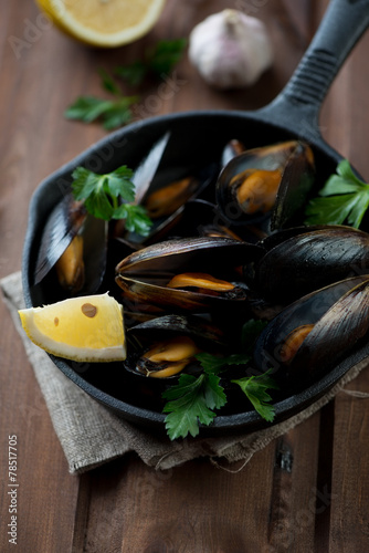 Boiled mussels with lemon, parsley and garlic, selective focus